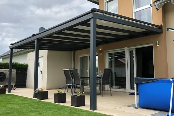 Glasdach in Anthrazit über einer Terrasse mit Gartenmöbeln